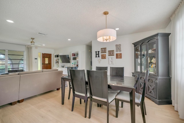 dining area with a textured ceiling, light hardwood / wood-style flooring, and ceiling fan