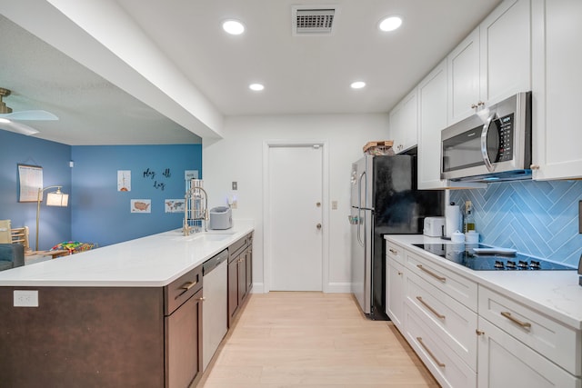 kitchen featuring sink, stainless steel appliances, light stone counters, light hardwood / wood-style flooring, and white cabinets