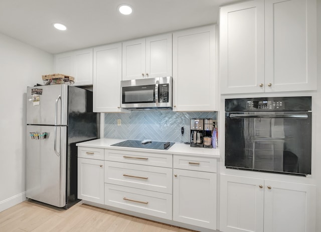 kitchen with light wood-type flooring, tasteful backsplash, white cabinetry, and black appliances