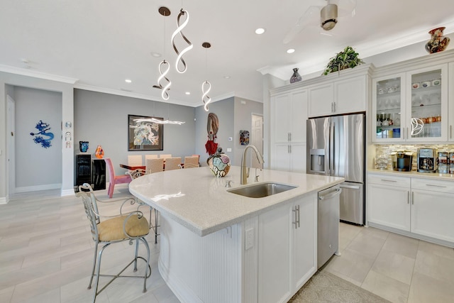 kitchen with a kitchen island with sink, sink, white cabinetry, appliances with stainless steel finishes, and decorative light fixtures