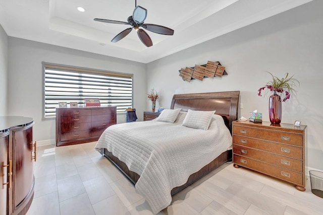 bedroom featuring ceiling fan, a raised ceiling, and light tile patterned floors