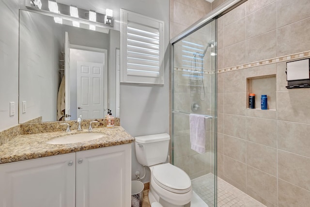 bathroom featuring vanity, a shower with shower door, and toilet