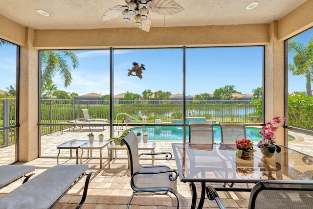 sunroom / solarium with a water view and ceiling fan