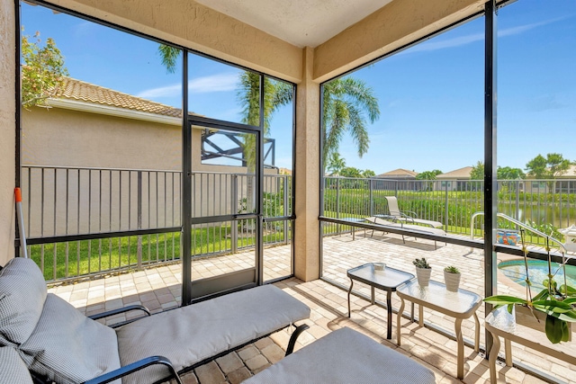 sunroom featuring a water view