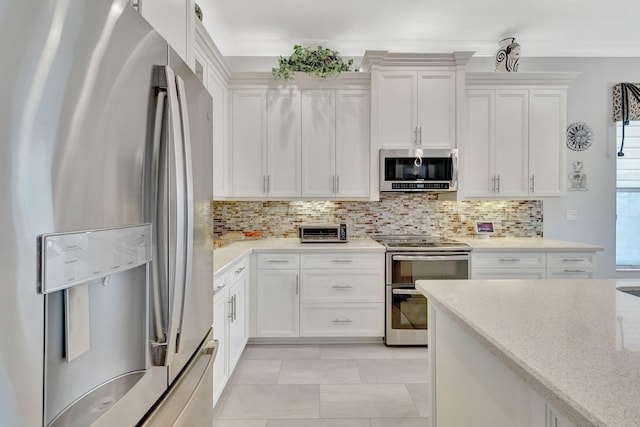 kitchen featuring stainless steel appliances, backsplash, light stone counters, and white cabinetry