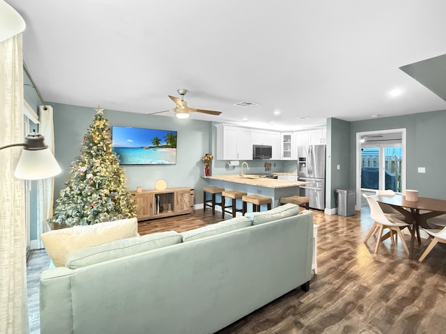 living room featuring ceiling fan, sink, and dark hardwood / wood-style flooring