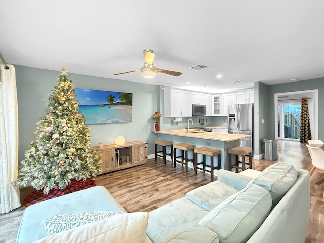 living room with light hardwood / wood-style floors, sink, and ceiling fan