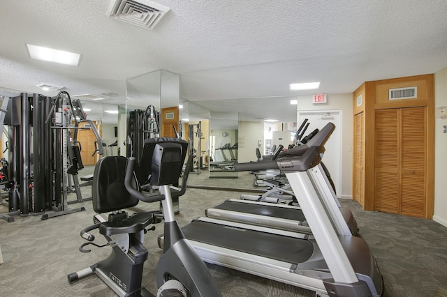 exercise room featuring carpet floors and a textured ceiling