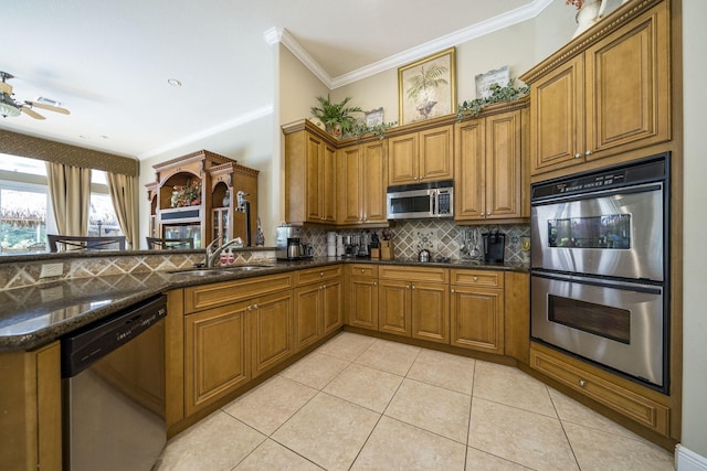 kitchen with dark stone countertops, sink, kitchen peninsula, and stainless steel appliances