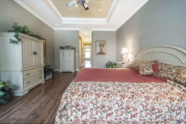 bedroom with ceiling fan, a raised ceiling, ornamental molding, and dark wood-type flooring