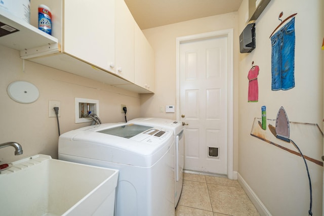 clothes washing area with washer and dryer, light tile patterned flooring, cabinets, and sink