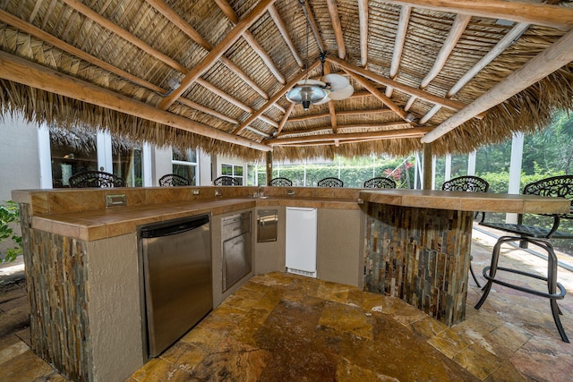 kitchen featuring tile countertops, stainless steel refrigerator, plenty of natural light, and lofted ceiling