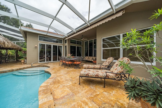 view of swimming pool featuring glass enclosure, ceiling fan, and a patio