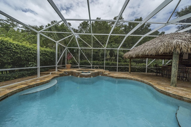 view of swimming pool with glass enclosure, a bar, an in ground hot tub, and a patio