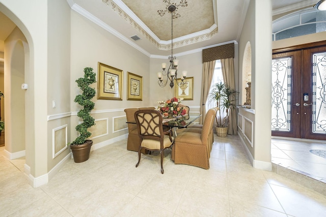 dining area featuring french doors, ornamental molding, a raised ceiling, light tile patterned floors, and a chandelier