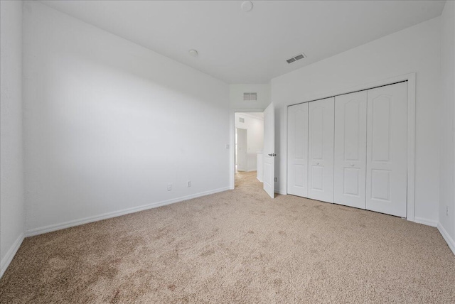 unfurnished bedroom featuring light colored carpet and a closet