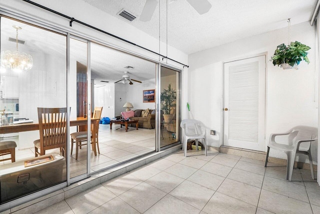 sunroom / solarium featuring ceiling fan with notable chandelier