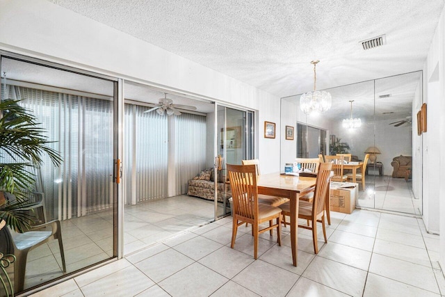 dining area with ceiling fan with notable chandelier, light tile patterned flooring, and a textured ceiling