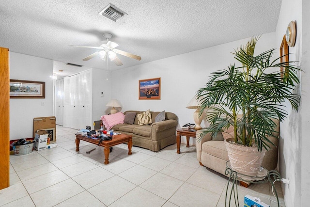 living room with ceiling fan, a textured ceiling, and light tile patterned floors