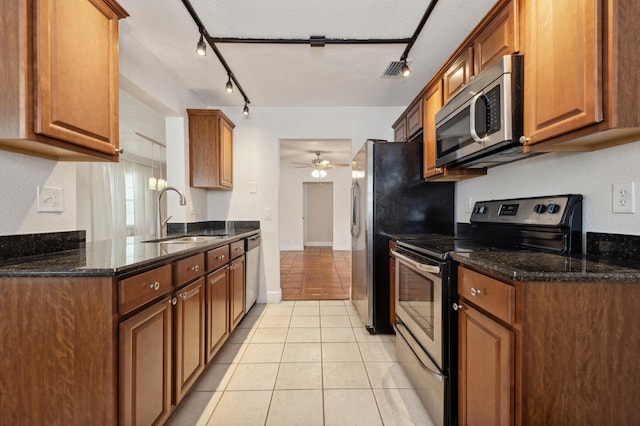 kitchen with ceiling fan, sink, dark stone countertops, light tile patterned floors, and appliances with stainless steel finishes