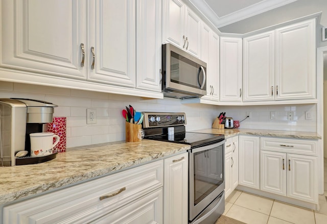 kitchen with light stone counters, white cabinets, light tile patterned floors, stainless steel appliances, and crown molding