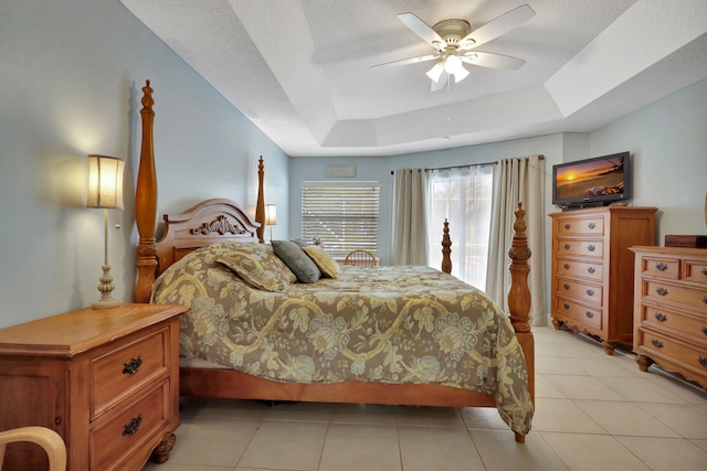 bedroom featuring ceiling fan, light tile patterned flooring, a tray ceiling, and a textured ceiling