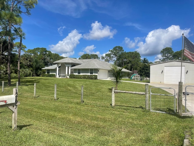 view of front of house featuring a garage, a front yard, and an outbuilding