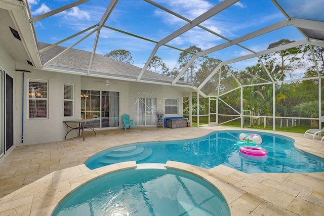 view of swimming pool featuring an in ground hot tub, glass enclosure, a patio area, and ceiling fan