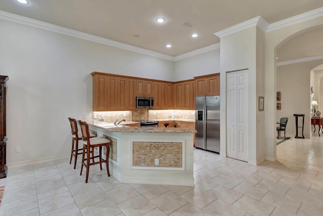 kitchen with light stone countertops, stainless steel appliances, a kitchen breakfast bar, kitchen peninsula, and crown molding