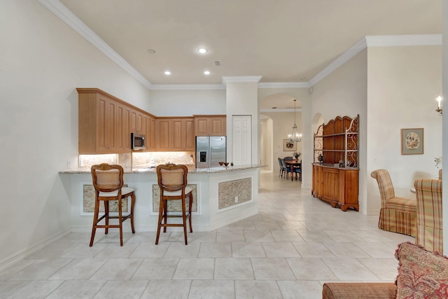 kitchen with a kitchen bar, kitchen peninsula, stainless steel appliances, and ornamental molding