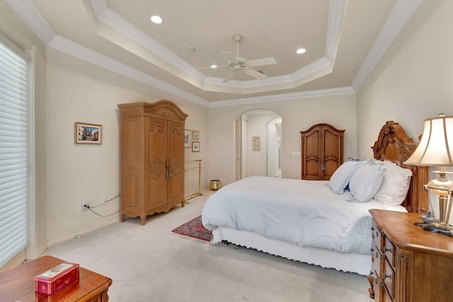 carpeted bedroom featuring a raised ceiling, ceiling fan, and crown molding