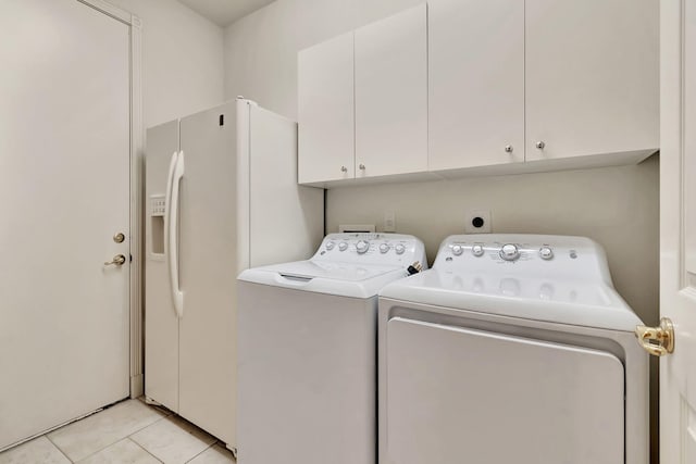 clothes washing area featuring light tile patterned flooring, cabinets, and washing machine and dryer