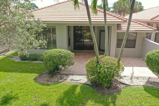 doorway to property with a yard and a patio