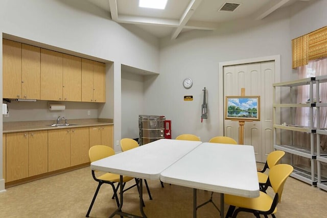 kitchen featuring beamed ceiling, light brown cabinetry, coffered ceiling, and sink