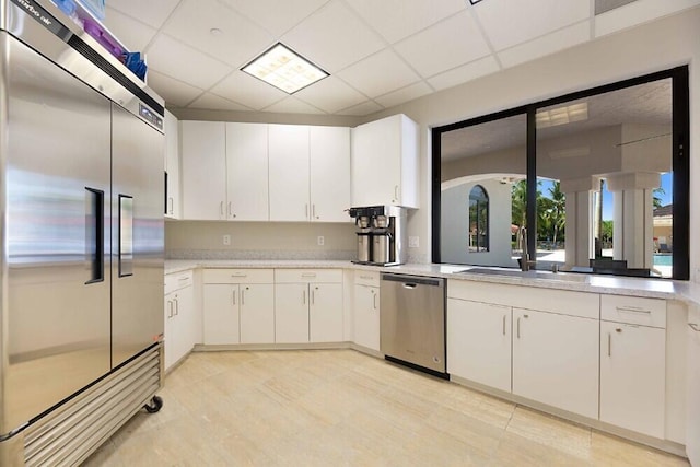 kitchen with white cabinets, a drop ceiling, sink, and appliances with stainless steel finishes