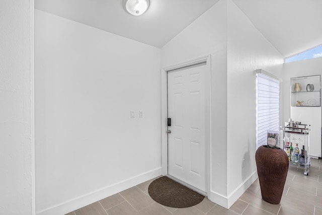 foyer featuring light tile patterned flooring and vaulted ceiling