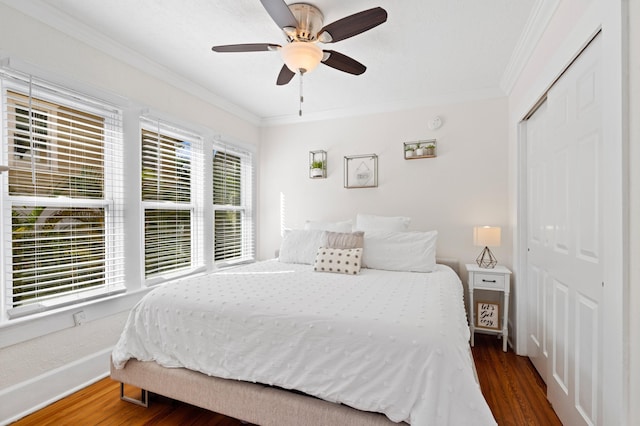 bedroom with dark hardwood / wood-style floors, a closet, ornamental molding, and ceiling fan