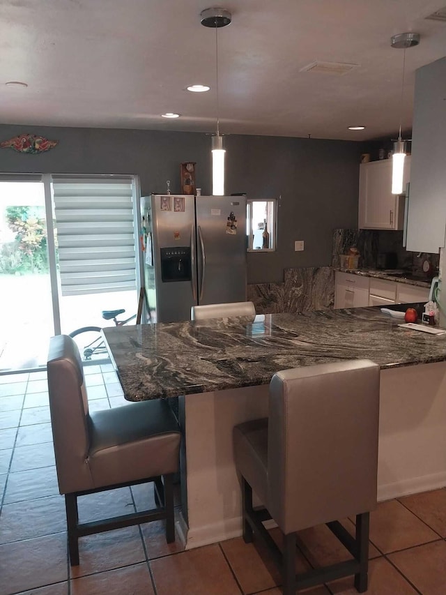 kitchen featuring kitchen peninsula, decorative light fixtures, white cabinets, and stainless steel refrigerator with ice dispenser