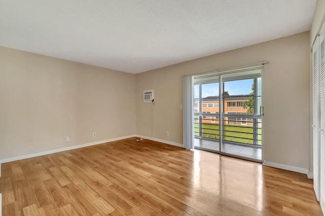 unfurnished room featuring light wood-type flooring and a wall unit AC