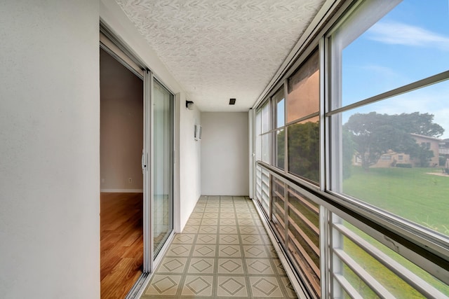 hallway with light wood-type flooring and a textured ceiling