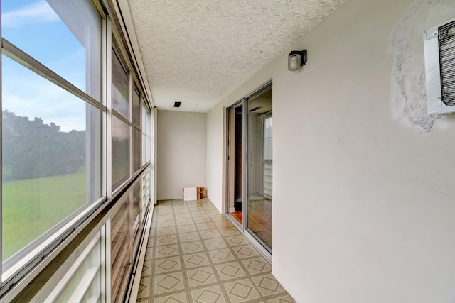 corridor with a textured ceiling, light tile patterned floors, and a wealth of natural light