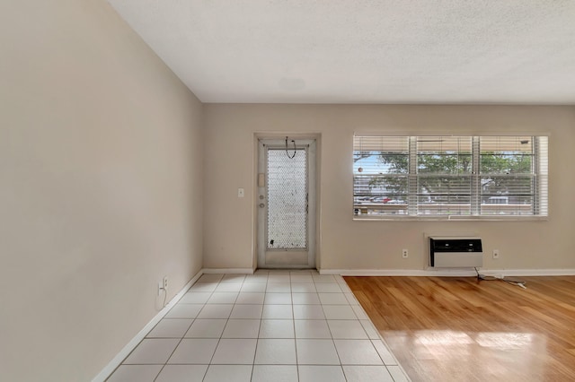 foyer entrance featuring heating unit, light hardwood / wood-style floors, and a textured ceiling