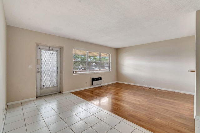 unfurnished room featuring light hardwood / wood-style floors and a textured ceiling