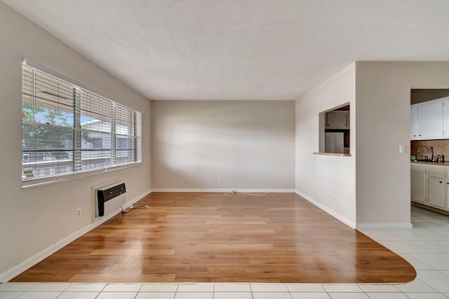 spare room with a wall mounted air conditioner, sink, light wood-type flooring, and a textured ceiling