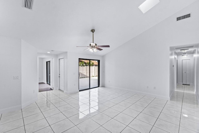 spare room with light tile patterned flooring, vaulted ceiling with skylight, and ceiling fan