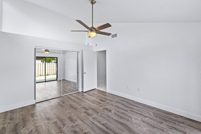 unfurnished bedroom featuring wood-type flooring, ceiling fan, high vaulted ceiling, and a closet