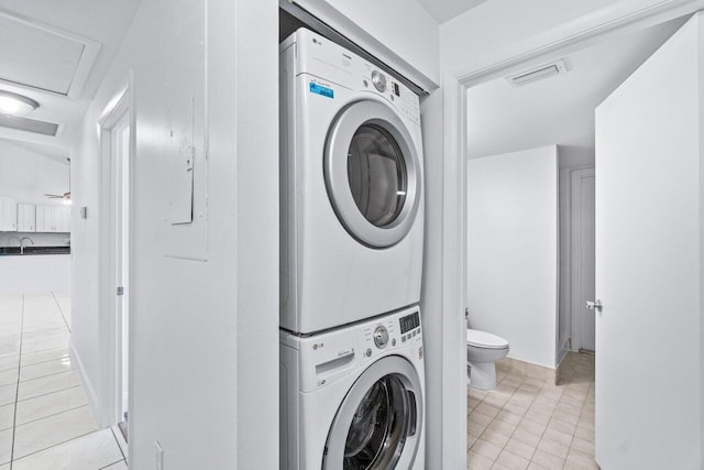 laundry area featuring stacked washer / drying machine, sink, and light tile patterned flooring