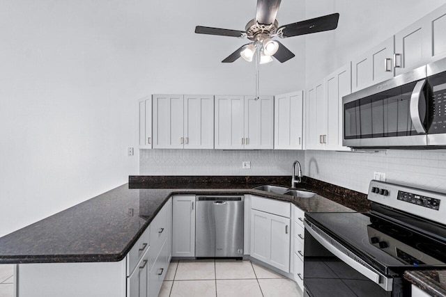 kitchen with sink, white cabinetry, stainless steel appliances, tasteful backsplash, and dark stone counters