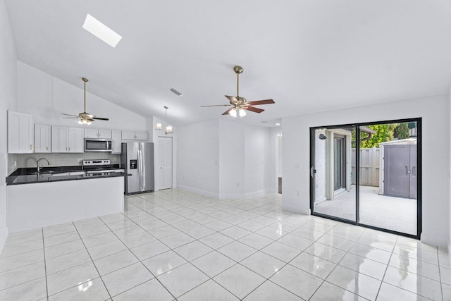 unfurnished living room featuring ceiling fan, a skylight, sink, and light tile patterned floors