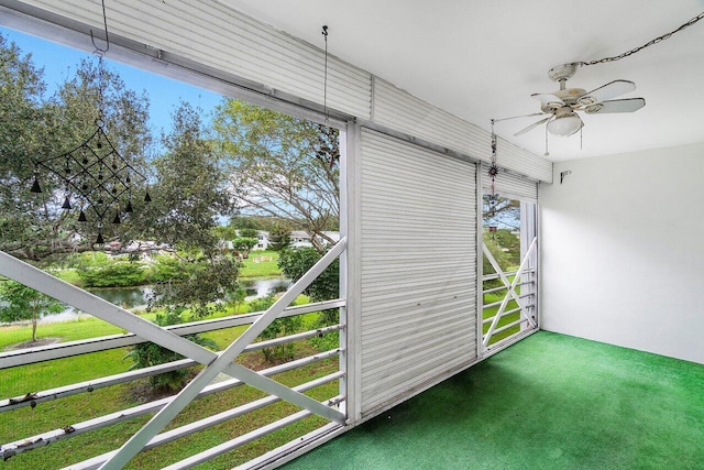 unfurnished sunroom featuring ceiling fan and a water view